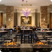 Modern eingerichtetes Restaurant mit Kaminfeuer und violettem Kronleuchter